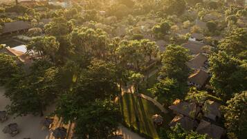Vista aérea de una zona residencial con casas, árboles y una playa con sombrillas.