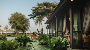 Un restaurante con vistas al mar, rodeado de exuberante vegetación y palmeras.