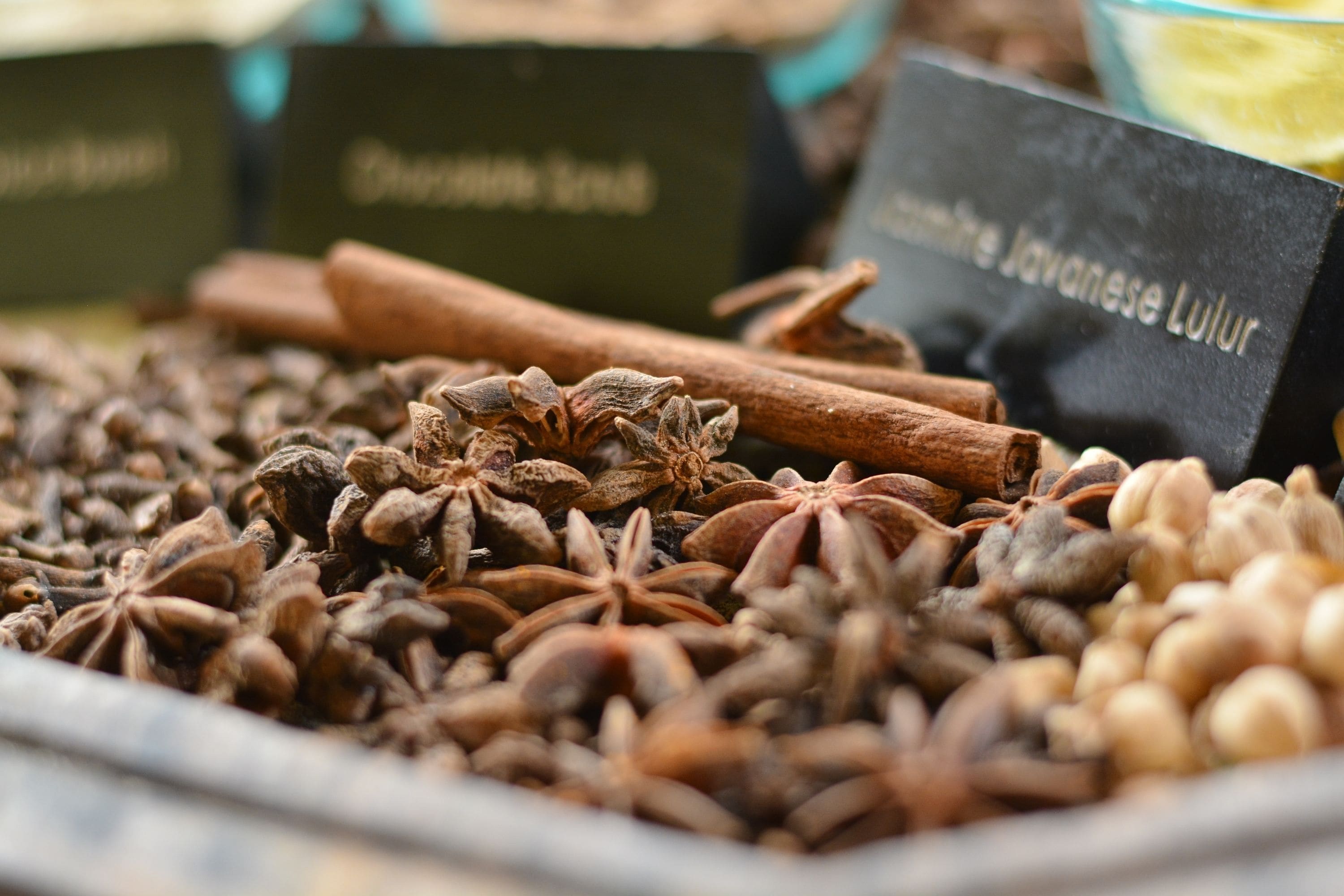 Variedad de especias, incluyendo anís estrellado, ramitas de canela y clavo de olor, con etiquetas que indican sus nombres.