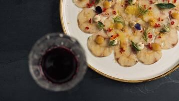 Un plato de comida con diferentes adornos y una copa de vino tinto.