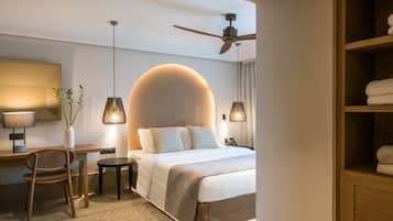 Een moderne hotelkamer met een groot bed, een bureau, een stoel, een plafondventilator en een kledingkast.