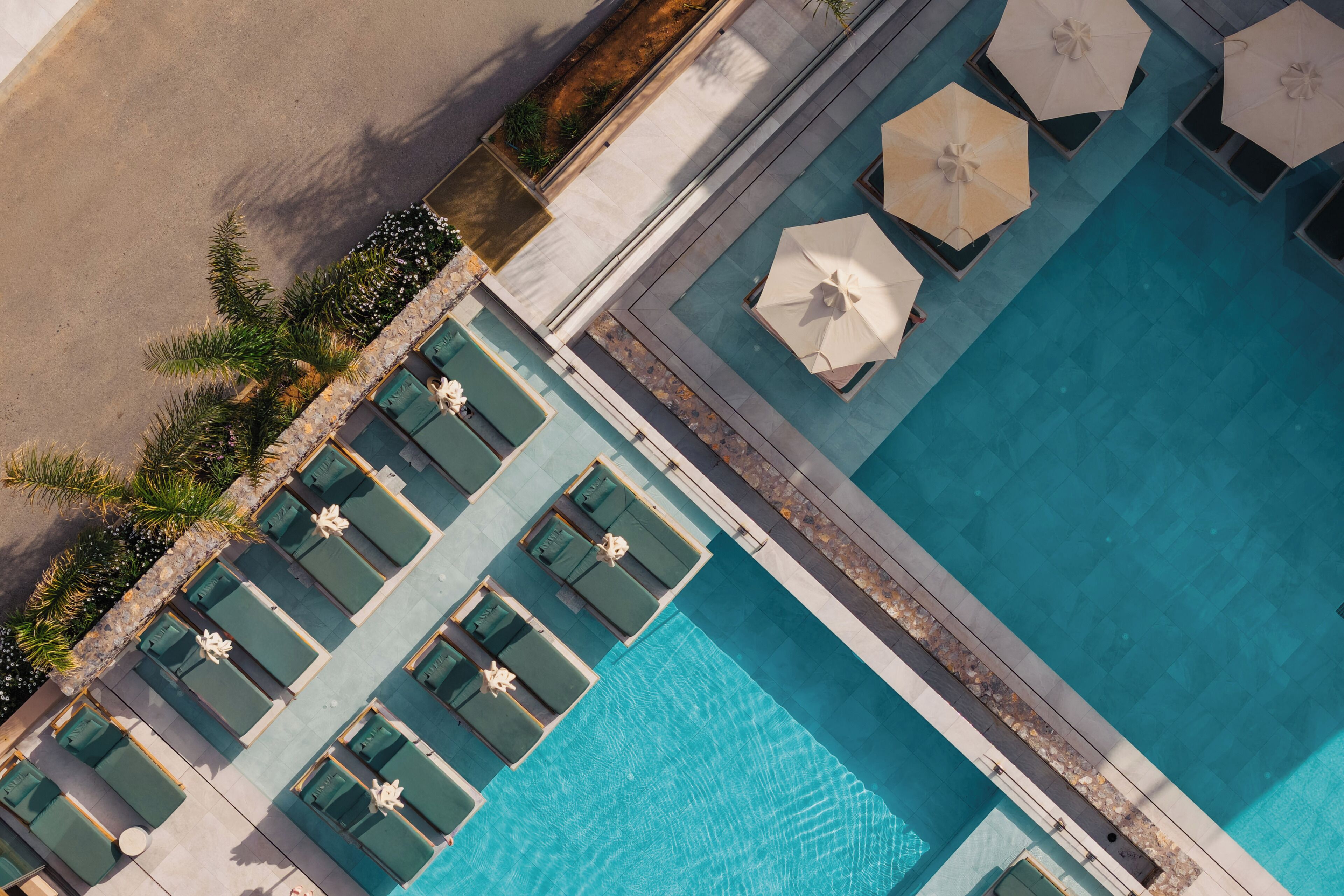 Vista aérea de uma piscina com várias áreas de estar e guarda-sóis.