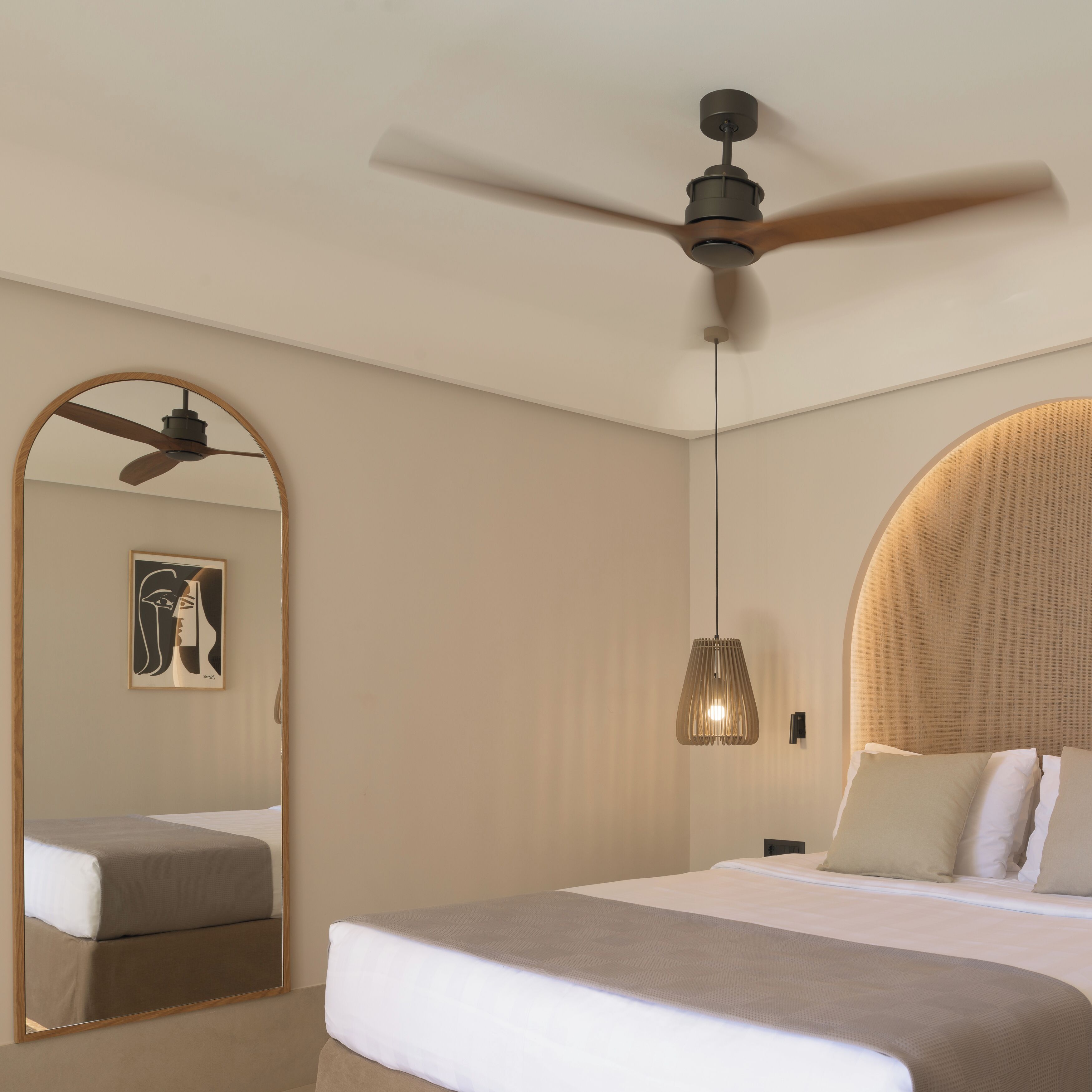 A modern hotel room with a bed, a ceiling fan, a pendant light, and a large mirror.