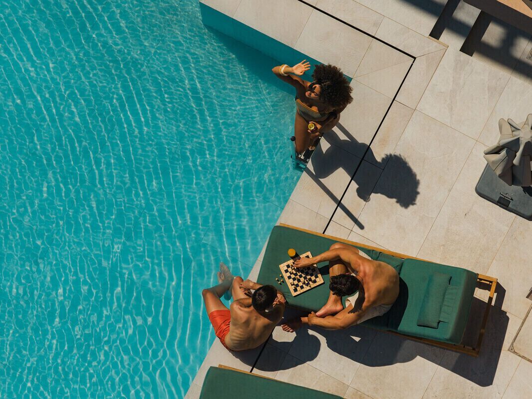 Zona junto a la piscina con dos tumbonas y un tablero de ajedrez.