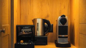 Eine Kaffeemaschine, ein Wasserkocher und eine Schachtel mit einer Kaffeemaschine auf einem Holzregal.