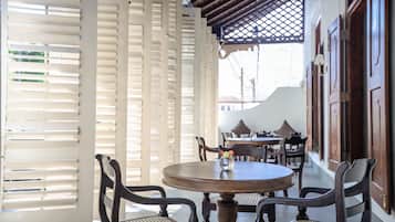 A dining area with a round table, two chairs, and a vase with flowers.