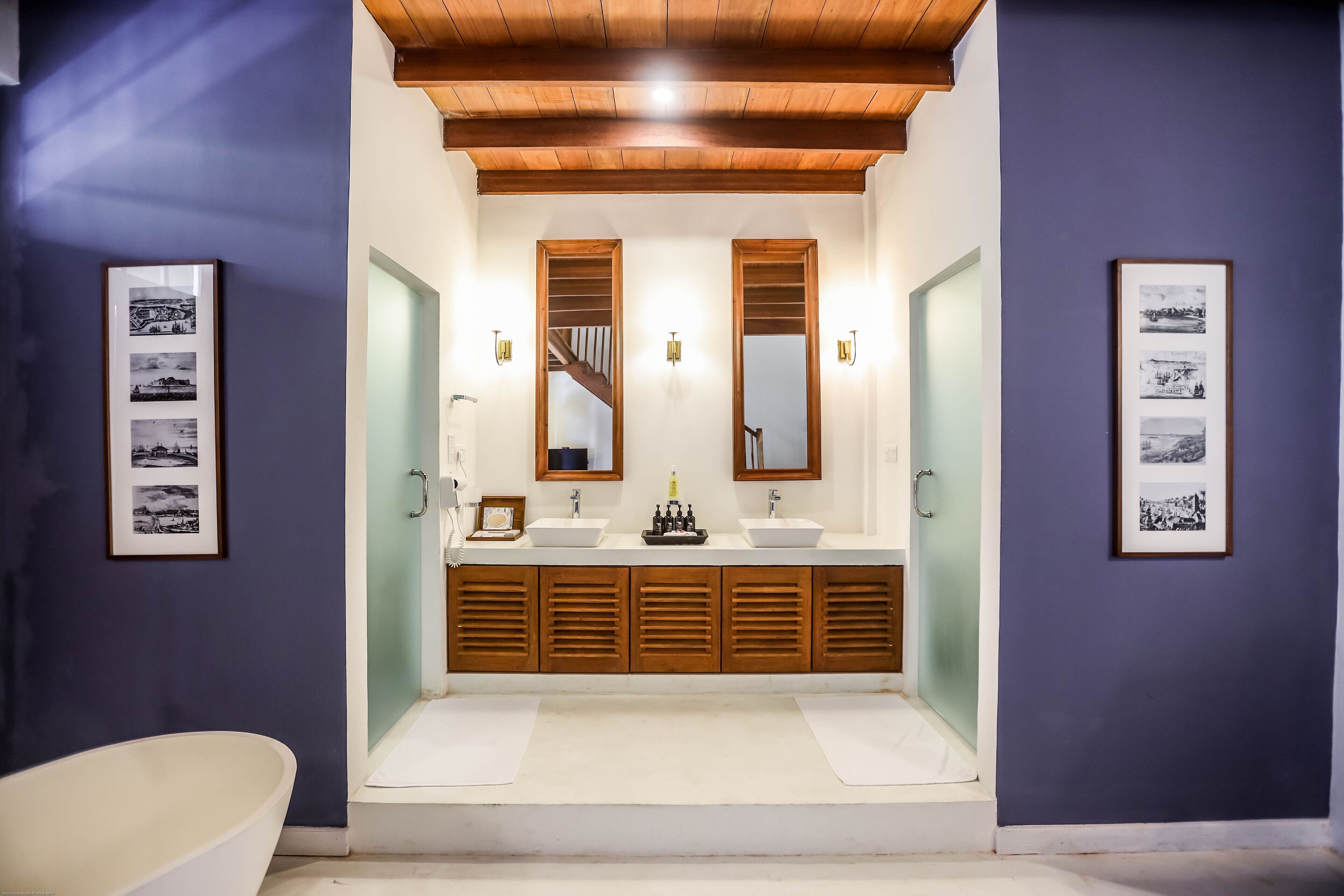 Une salle de bain avec un meuble-lavabo en bois, deux vasques et une baignoire.