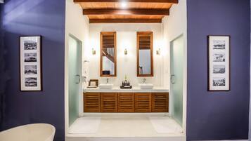 Une salle de bain avec un meuble-lavabo en bois, deux vasques et une baignoire.