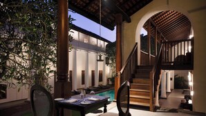 A dining area with a table set for two, a staircase, and a pool in the background. - Galle Fort Hotel (Galle)