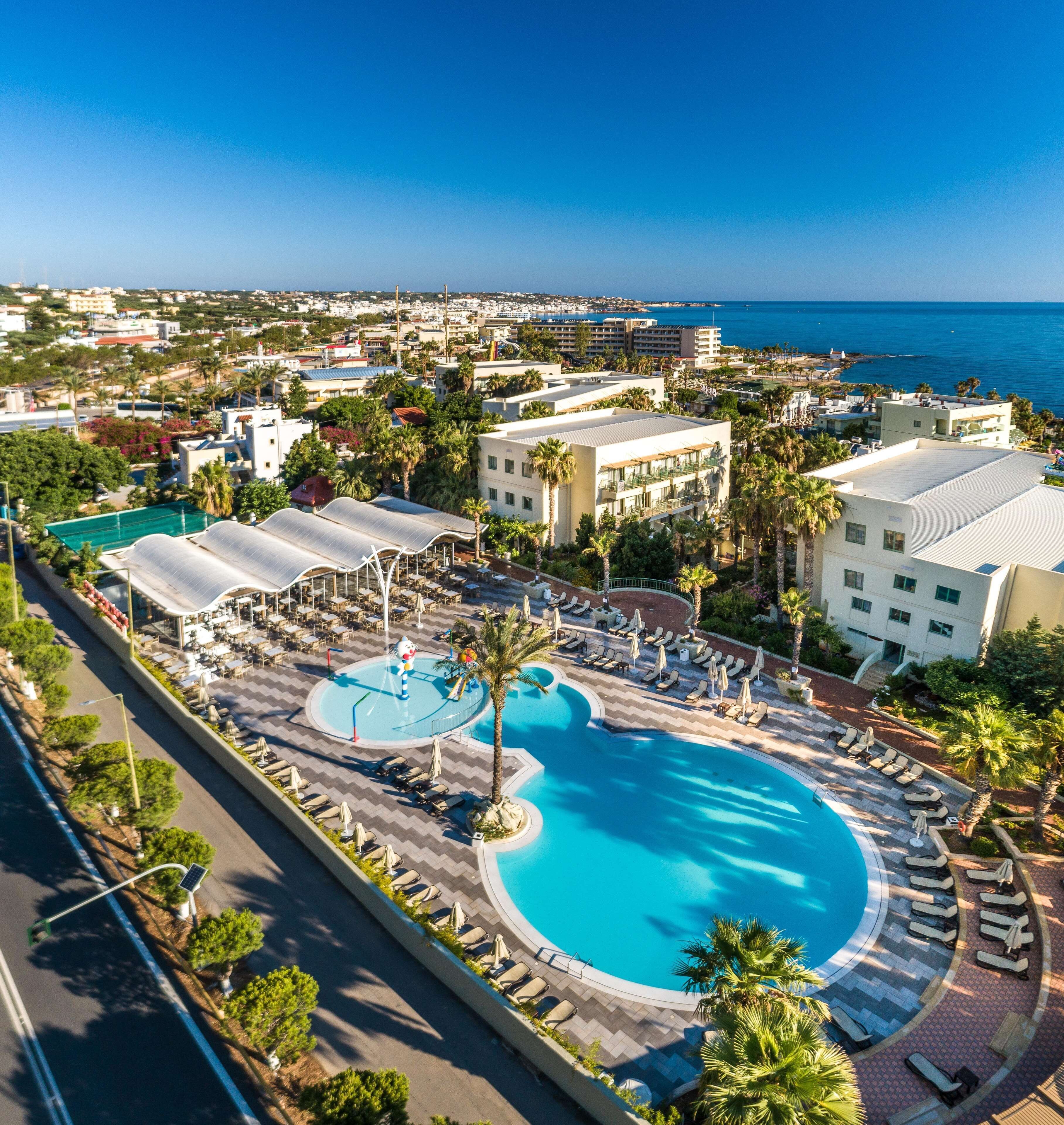 Un resort con una piscina grande, tumbonas y vista al océano.