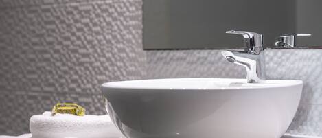 Un lavamanos de cerámica blanca con un grifo moderno, una toalla y un espejo en un baño con pared texturizada.