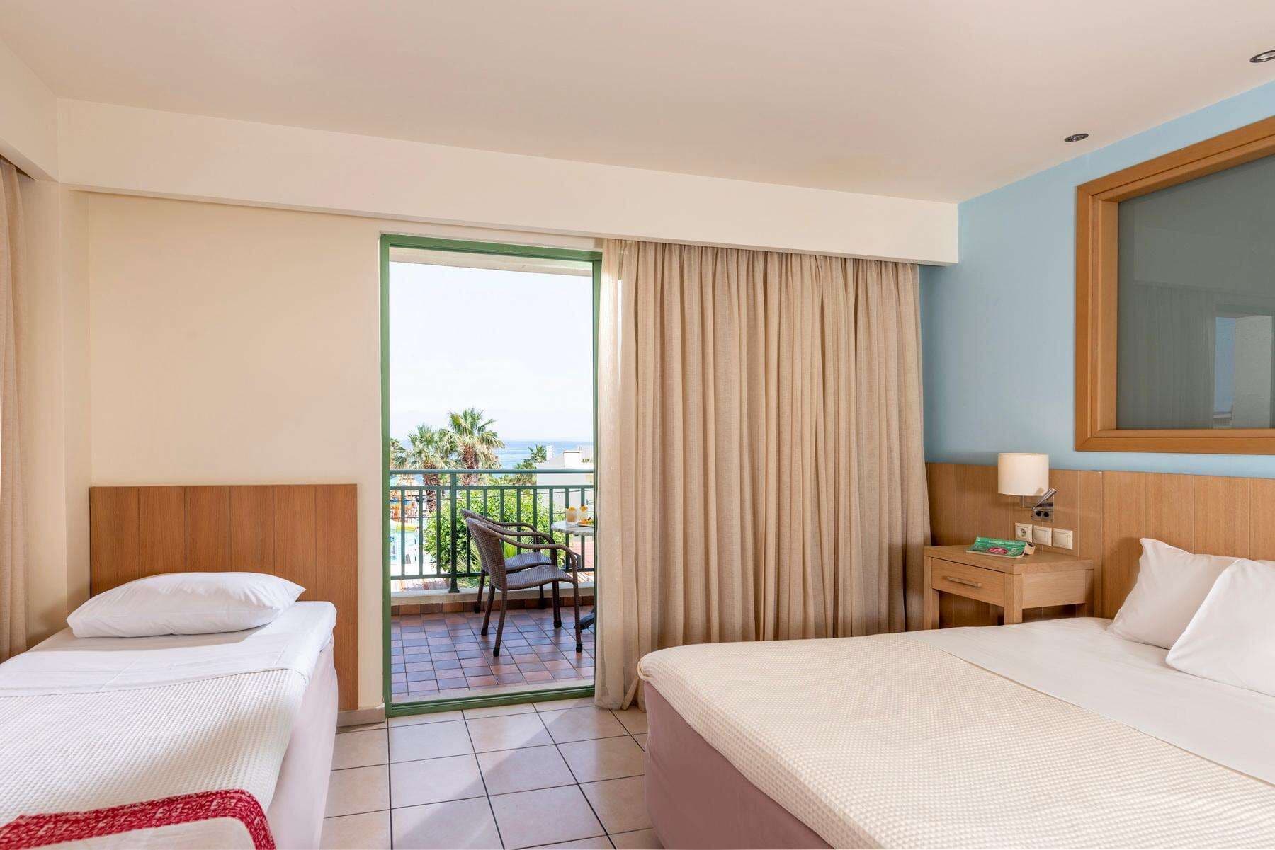 A hotel room with a bed, a chair, a nightstand, and a view of the balcony.
