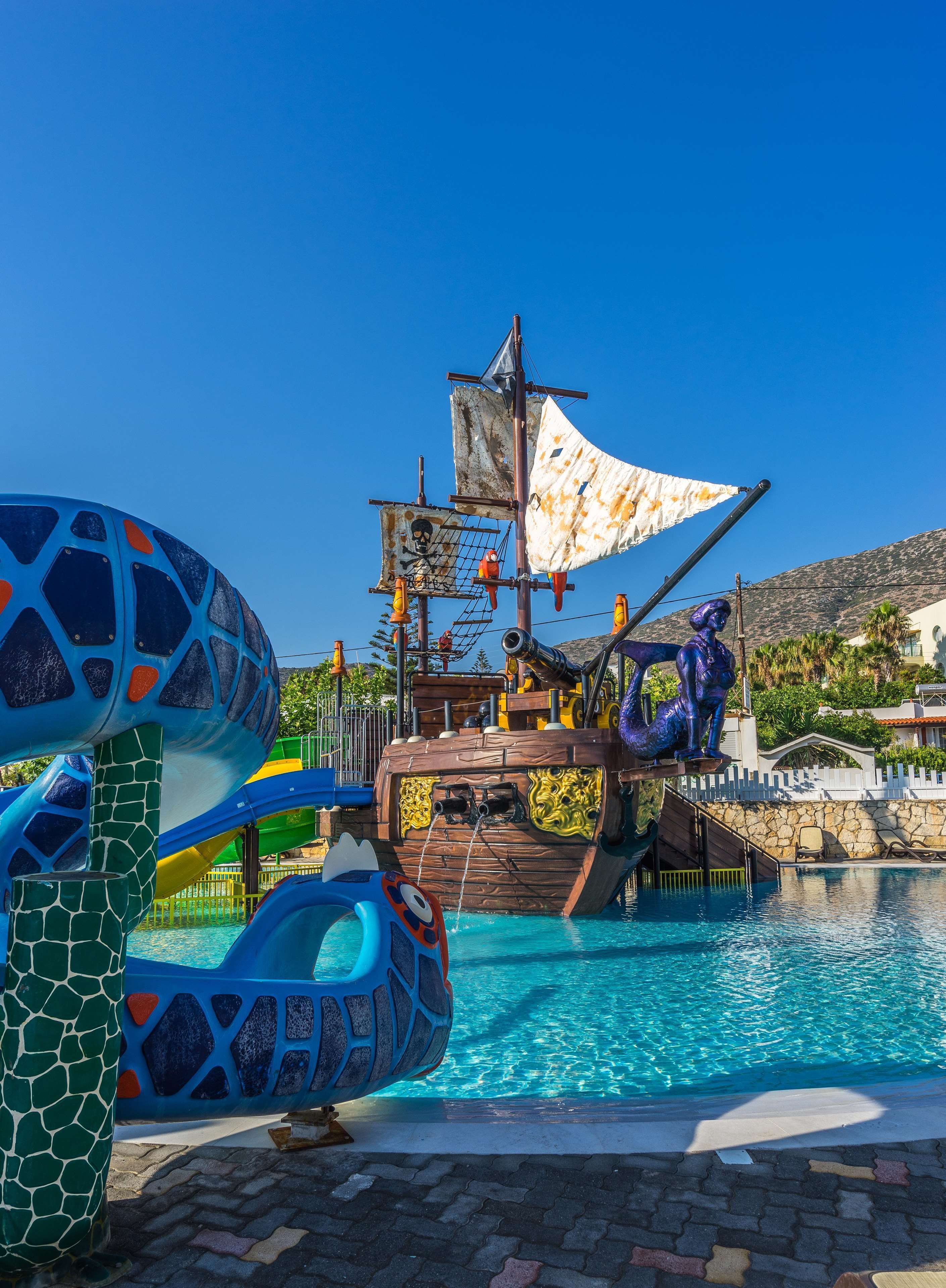 Um parque aquático com tema de pirata, apresentando uma estrutura de navio, escorregas e piscina.
