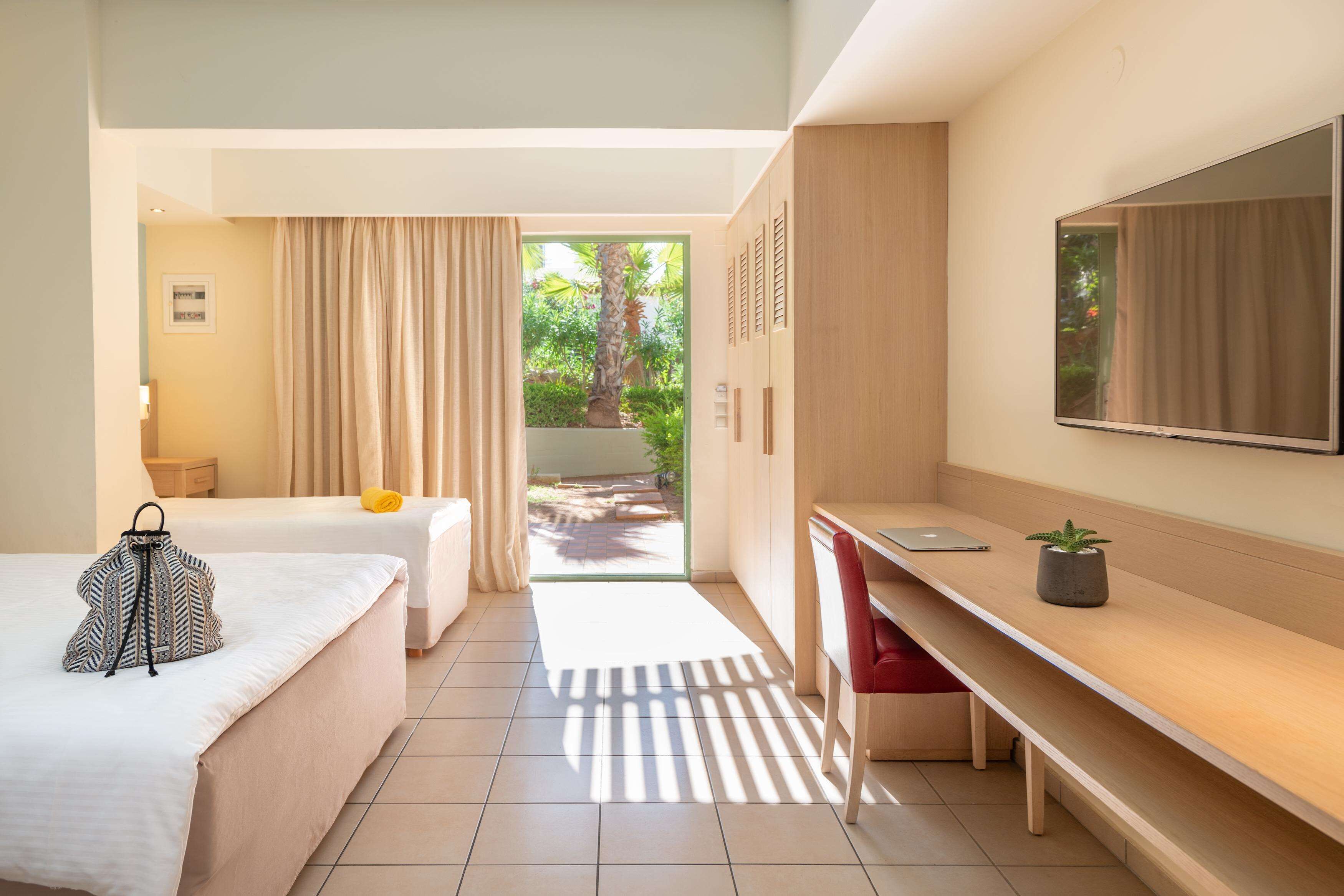 A hotel room with a bed, a desk, a chair, a mirror, and a view of the outdoors.