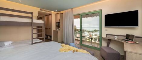A hotel room with a bunk bed, a desk with a laptop, a TV, and a balcony with a view.