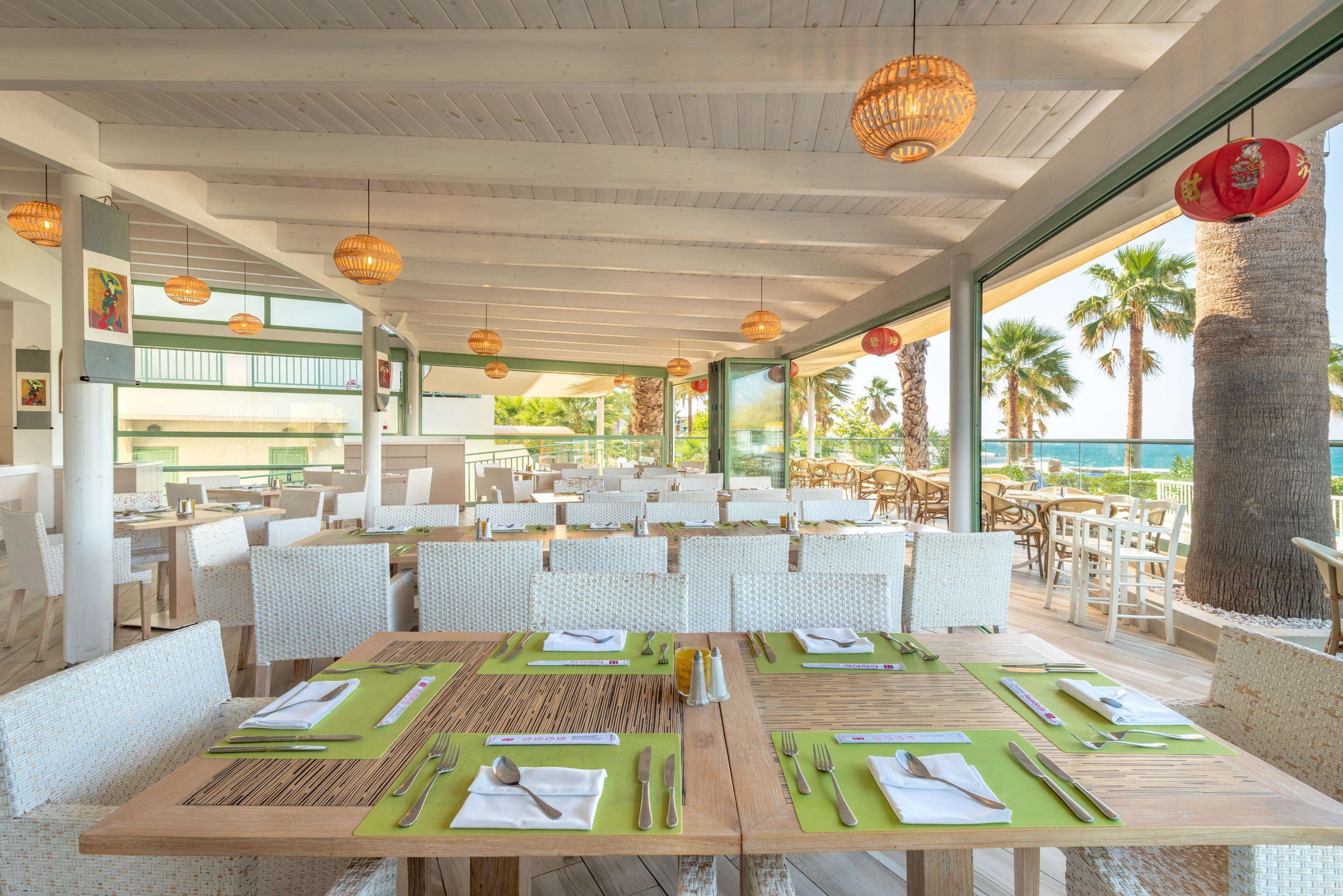A restaurant with outdoor seating, wooden tables, and green placemats.