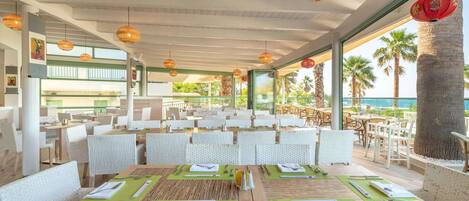 A restaurant with outdoor seating, wooden tables, and green placemats.