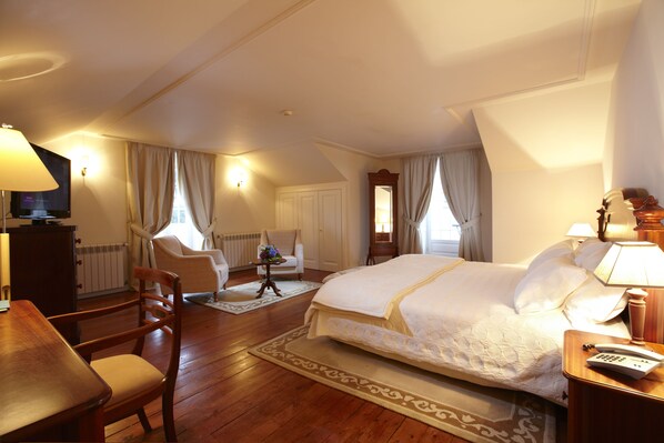 A hotel room with a large bed, a desk, a chair, a TV, and a lamp. - PortoBay Serra Golf (Santa Cruz)