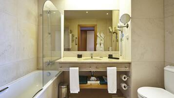 Un baño moderno con ducha de vidrio, un espejo grande, un lavamanos con toallero y un inodoro.