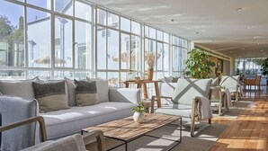 Un espacio interior amplio con un gran ventanal, un sofá, sillas y una mesa de centro.