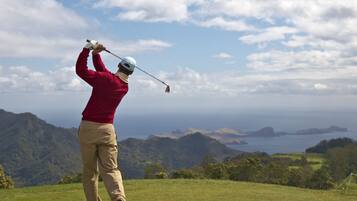Enjoy a serene golfing experience with a picturesque view of the surrounding landscape and distant hills.
