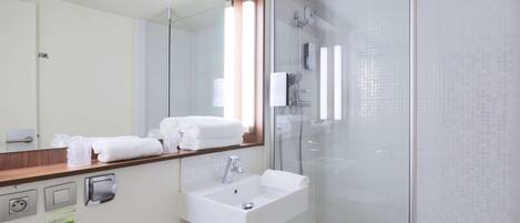 A modern bathroom with a glass-enclosed shower, a white sink, and a mirror above it.