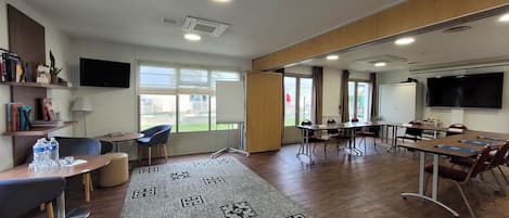 Un salón de conferencias con una gran mesa, sillas, una pizarra y una pantalla de televisión.