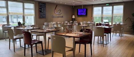 Um restaurante com mesas e cadeiras dispostas para refeições.