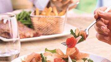 A dining table with a plate of food, a basket of fries, and a glass of water.