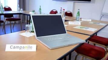 Ein Konferenzraum mit einem Laptop auf dem Tisch, Namensschildern und roten Stühlen.