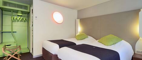 Habitación de hotel con dos camas, una unidad mural verde y una silla de madera.