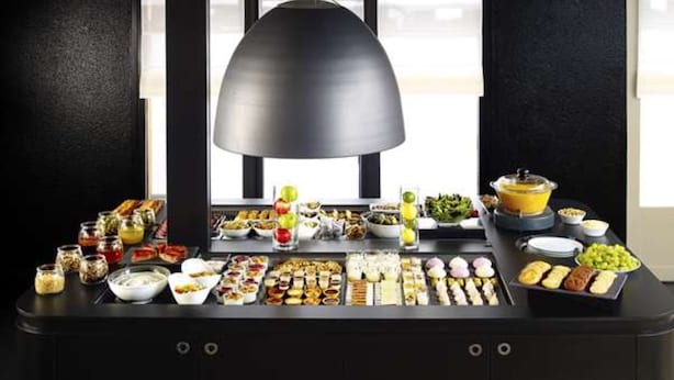 Una mesa de buffet con diversos platos y una lámpara negra grande.