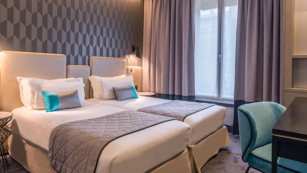 Et hotelværelse med to senge, et skrivebord og en stol.