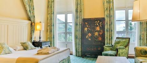 Ein Hotelzimmer mit Bett, Sessel, Tisch und Nachttisch.