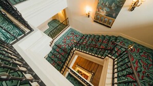 A multi-level staircase with ornate railings and patterned carpet. - Palacio Urgoiti (Mungia)