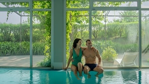 A couple sitting by an indoor pool with a view of greenery outside. - Palacio Urgoiti (Mungia)