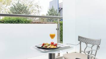 Un balcón con una mesa de comedor, una silla y un plato de fruta y jugo.