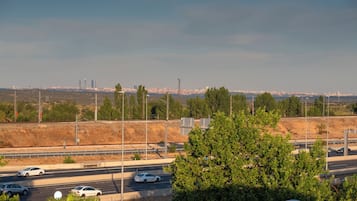 Una autopista con varios carriles y vehículos, rodeada de vegetación y un horizonte urbano distante.