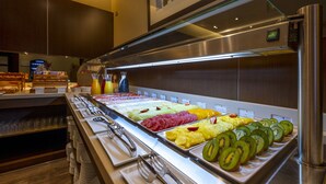 Un buffet proposant une variété de plats, notamment des fruits, des viandes et des boissons.