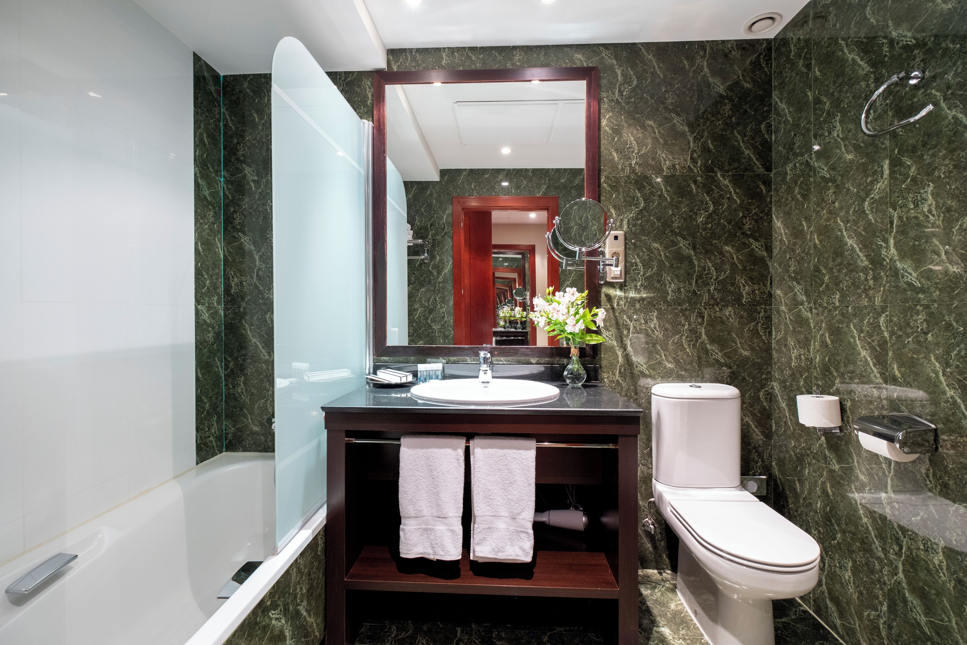 Un baño moderno con cabina de ducha de vidrio, un lavabo blanco y un inodoro.