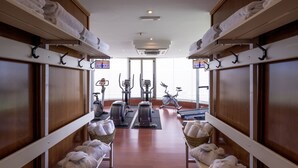 Une salle de sport équipée de matériel d’exercice, avec des serviettes et une grande fenêtre.
