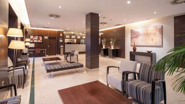 Un hall d’hôtel moderne avec un comptoir d’accueil, un espace salon et des œuvres d’art accrochées aux murs.