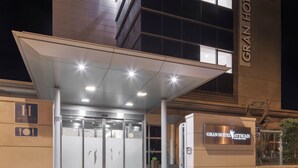 L’entrée d’un hôtel, avec un passage couvert, des portes en verre et une enseigne indiquant « GRAN HOTEL LAS ROZAS ».