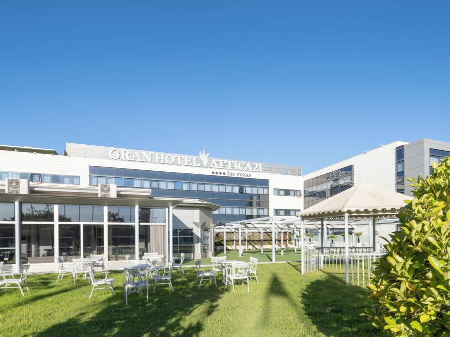 A hotel with a modern facade, outdoor seating area, and a clear blue sky.