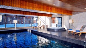 Piscina interior con sillones de descanso y bañera de hidromasaje.