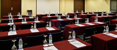 A conference room with multiple tables, each equipped with water bottles, glasses, and papers.