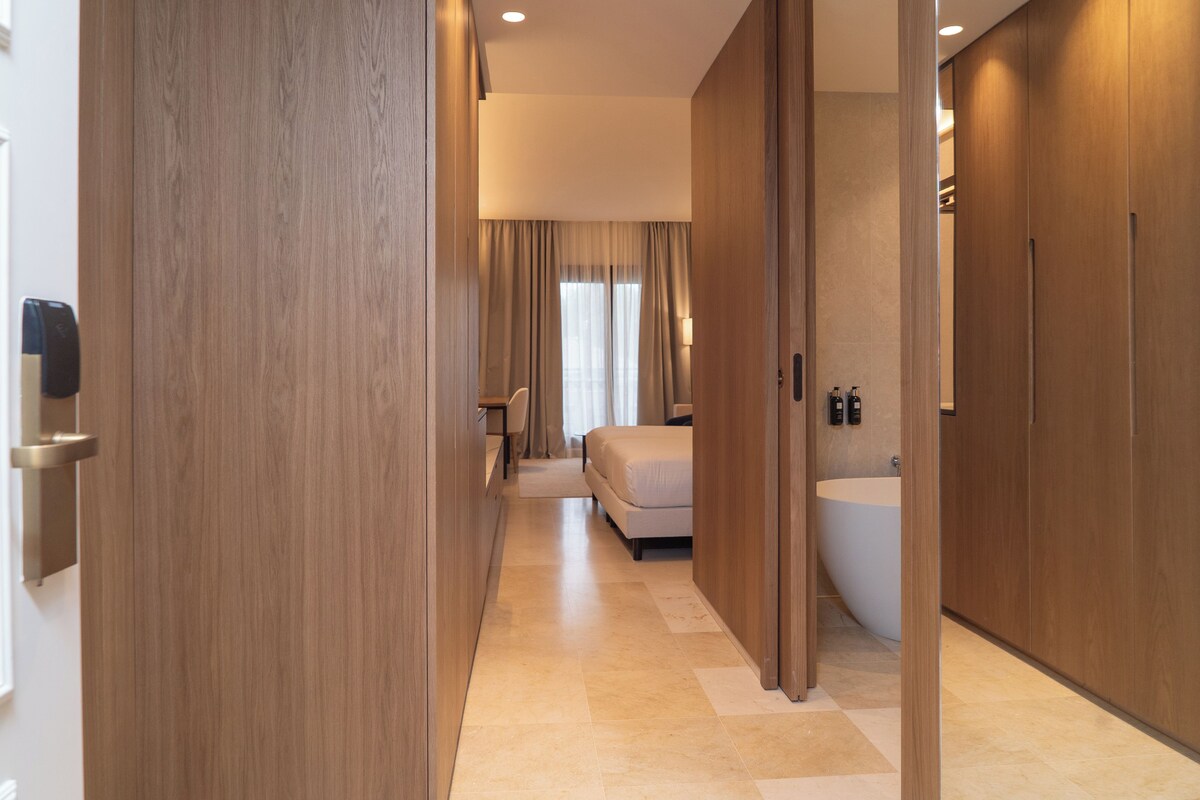 A hotel room with a large bathtub, a bed, and a desk.