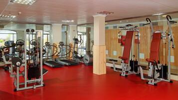 Ein Fitnessstudio mit Laufbändern, Kraftgeräten und einem roten Boden.