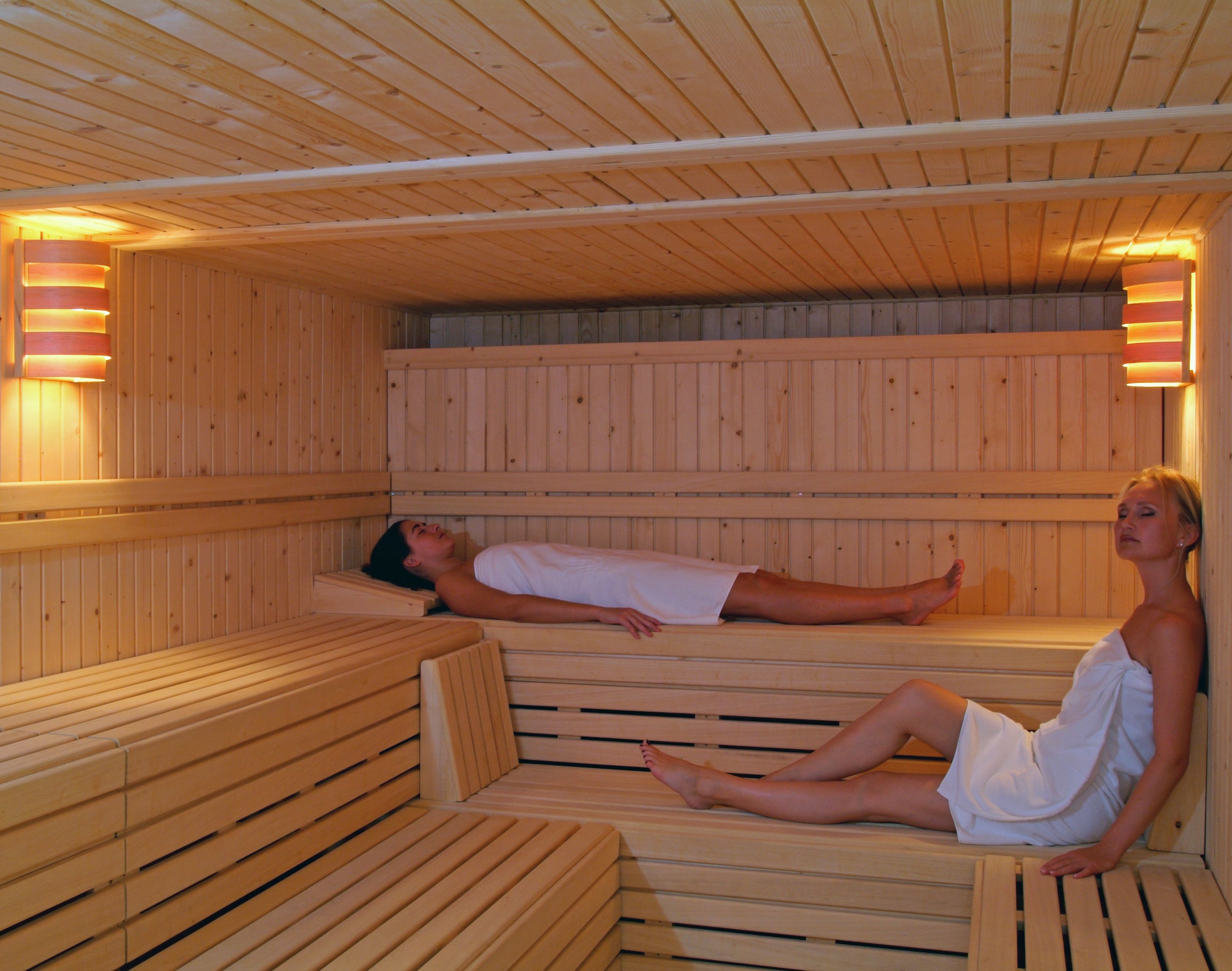 Een sauna met houten banken en een persoon die ligt.