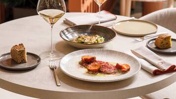 A round dining table with plates of food, glasses of wine, and cutlery.